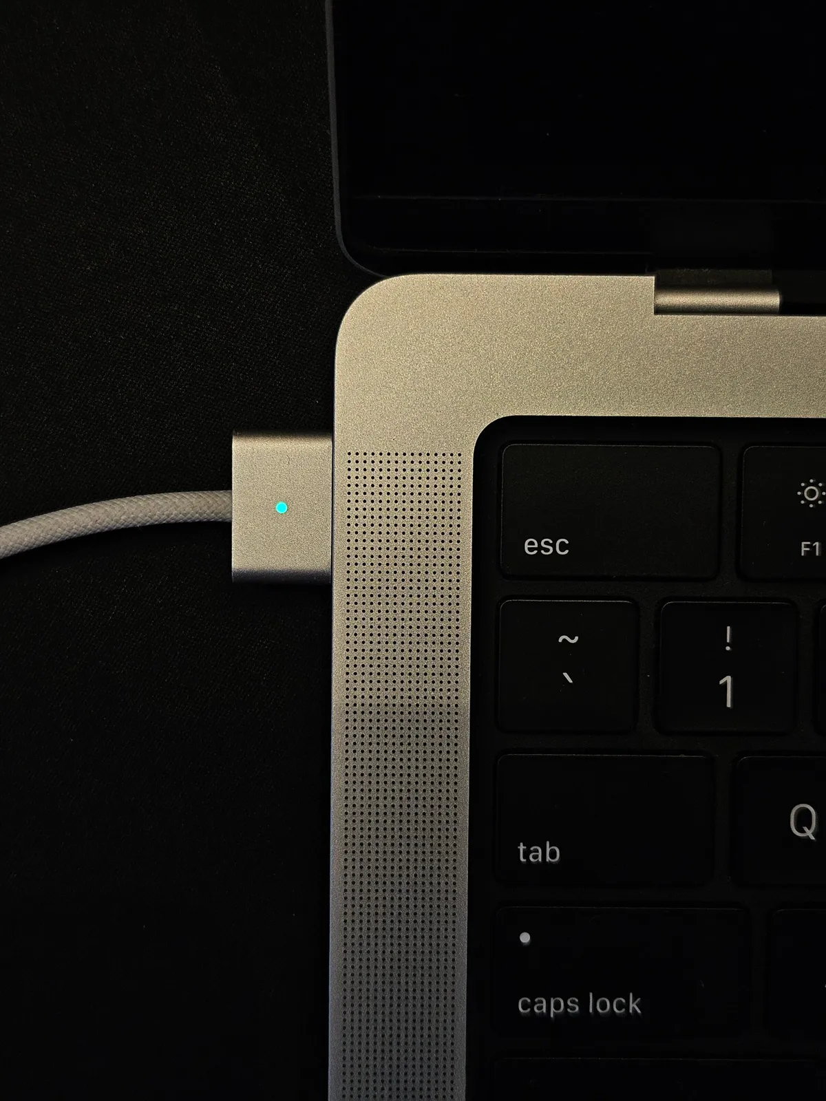 A MacBook connected to its charger with the charging light on