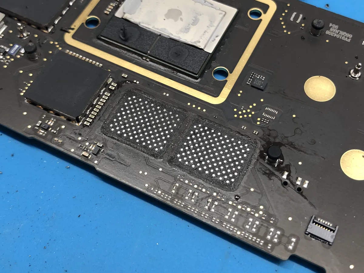 A MacBook Pro logic board with its storage chips being replaced